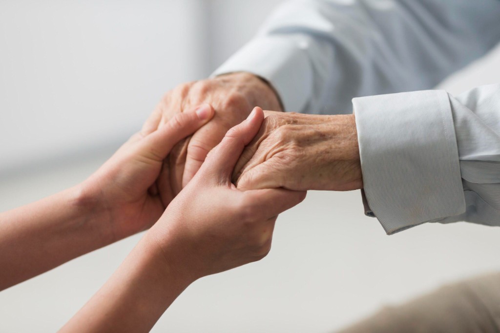 A younger person holding an older person's hand